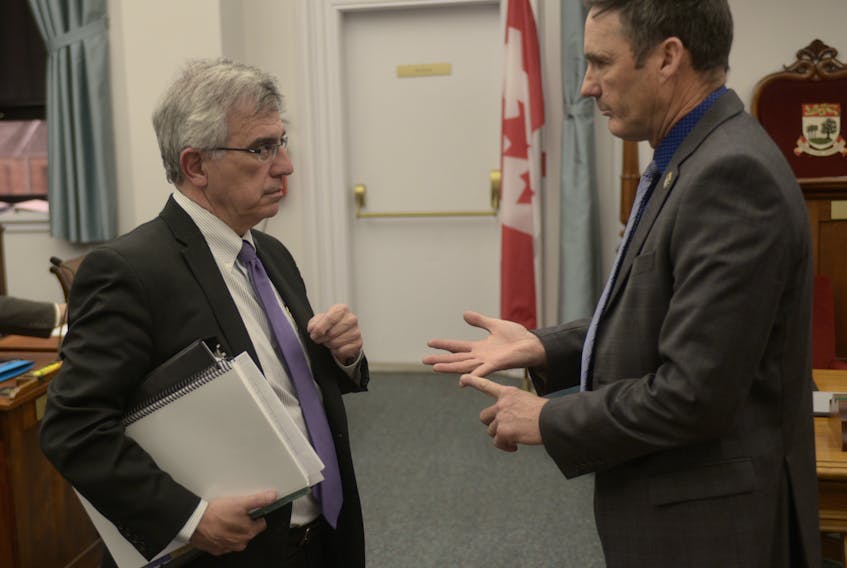 Opposition MLA Jamie Fox, right, chats with Communities, Land and Environment Minister Richard Brown prior to Tuesday’s question period.