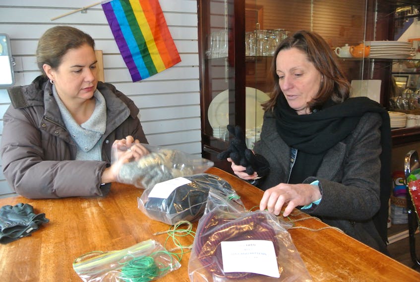 Jennifer Furlong (left) and Colleen Dowe of Empowering Beyond Barriers prepare bags of gloves and hats to place on utility poles on Victoria Street in downtown Amherst.
