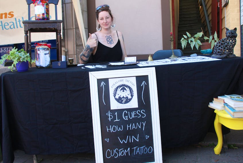 Emily Kane, from Folklore Tattoo, pictured taking part in the Antigonish Highland Games Street Fair July 4. She gestures towards a jar of jelly beans being used in a contest. Kane will be celebrating the one-year anniversary of her Main Street business July 27 and 28.