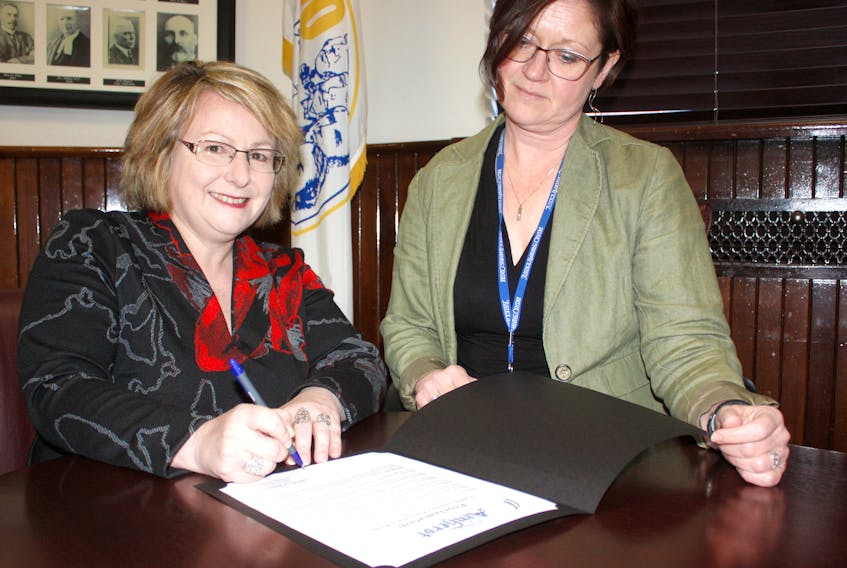 Lydia Quinn, domestic violence case co-ordinator Community, Indigenous and Diversity Police Services RCMP/Police, North East Nova and a member of the Interagency Committee on Family and Sexualized Violence, watches as Deputy-Mayor Sheila Christie signs a proclmation proclaiming Feb. 11 to Feb. 17 Family Violence Prevention Week in the Town of Amherst