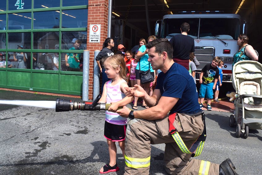 Little Lexi Barbour was one of dozens of children who enjoyed spraying a hose at a traffic cone representing a mock fire and earlier sat on the driving seat of a fire truck, helped along by firefighter Skyler Blackie. Earlier, firefighters read to children at the library before taking them on a guided tour of the station and also showed them their rescue equipment.