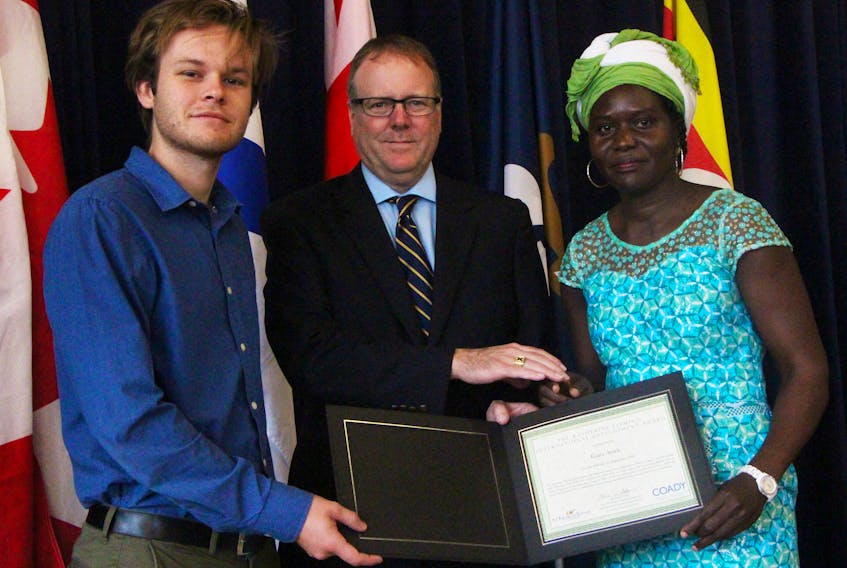 Alex Zutt (left), a son of the late Katherine Fleming, as well as George Fleming Jr., Katherine’s brother, present Coady International Institute Diploma in Development Leadership program participant Grace Arach with the Katherine Fleming International Development Award, during the Sept. 29 ceremony.