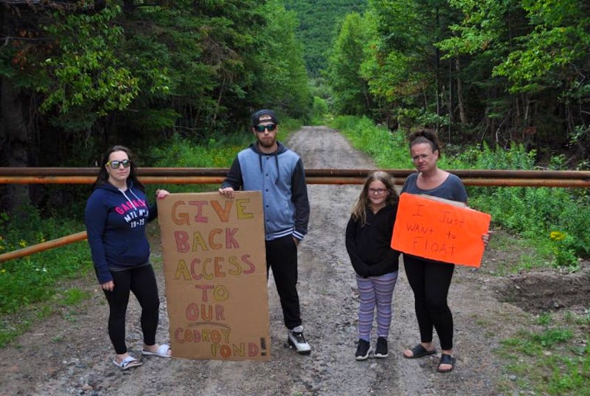 Some of the protesters hold signs in front of a metal gate, which nearby landowner Charles Brake has erected to prohibit access to Codroy Pond. From left: Alicia Bennett, Edward Skinner, Abby Pear, Chantell O’Quinn.