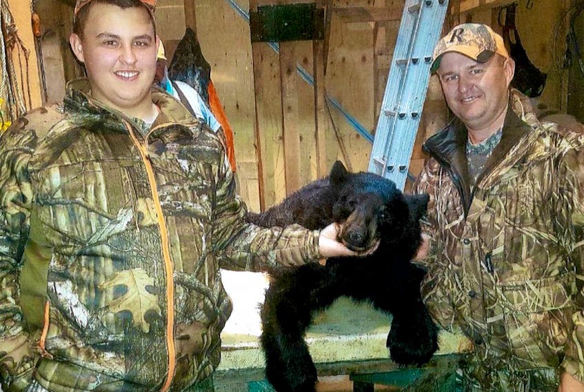 Leo Strickland and his father, James, pose with Leo’s first kill – a 120-pound black bear.