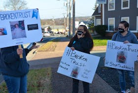 People protesting alleged abuses by dentist Errol Gaum hold up signs along Bedford Highway in front of the dental clinic Saturday morning.