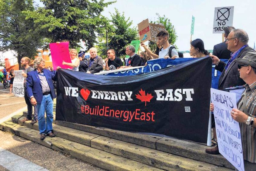 Supporters of the Energy East pipeline hold a banner in front of one held by protesters during a rally on Aug. 24, 2018 on the Halifax waterfront.