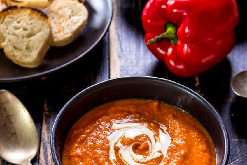 Delicious pumpkin soup with heavy cream with red bell pepper, bread toasts, lentil, tomatoes