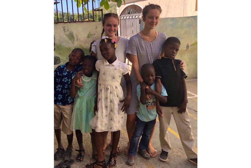 Lilly Gillespie, back left, and Paige Biggley are embracing their experience working in an orphanage in Haiti. They are safe from the civil unrest in the country and hope to remain until early May.