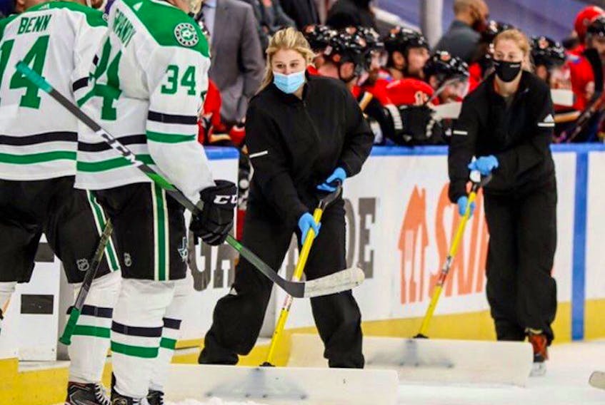 Taylor Hoeg (left) a native of Southampton, N.S., shovels snow at the Rogers Place in Edmonton during the NHL playoffs. She is a member of the Edmonton Oilers’ Orange & Blue Ice Crew and is working inside the NHL playoff bubble.