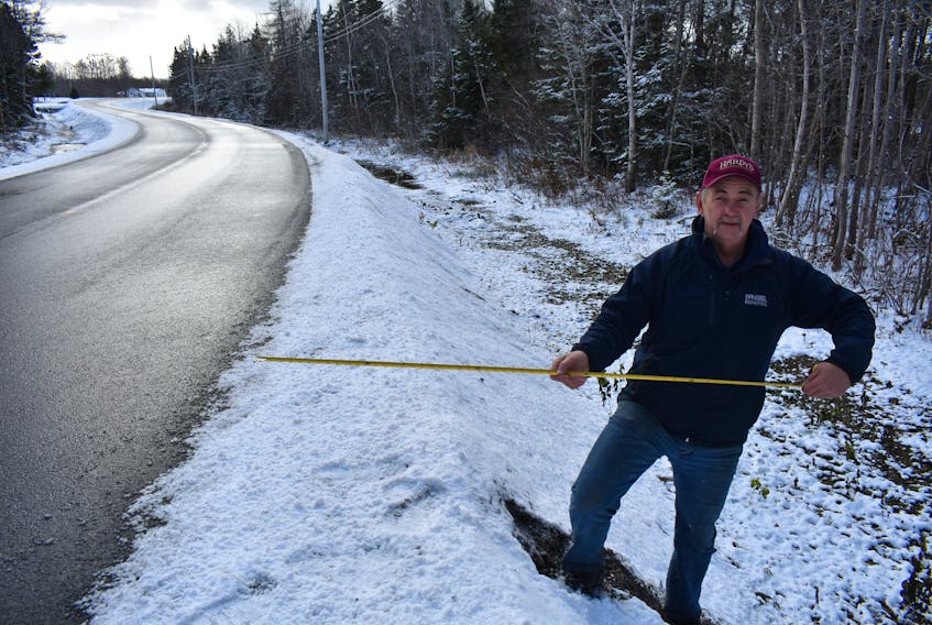 Kevin Hard measures the shoulder at a part of Hills Road on Nov. 21 to see if it meets provincial regulation for a minor collector F series roadway. These specifications call for shoulders to be 1.5m (59 inches) wide. At this spot the shoulder measured almost 26 inches.