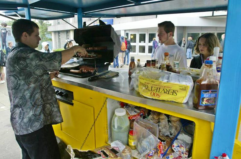 A hotdog vendor sells hotdogs to students in front of the Dalhousie University student union building in Halifax.