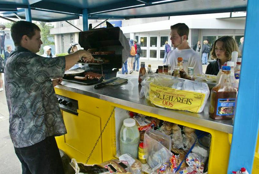 A hotdog vendor sells hotdogs to students in front of the Dalhousie University student union building in Halifax.