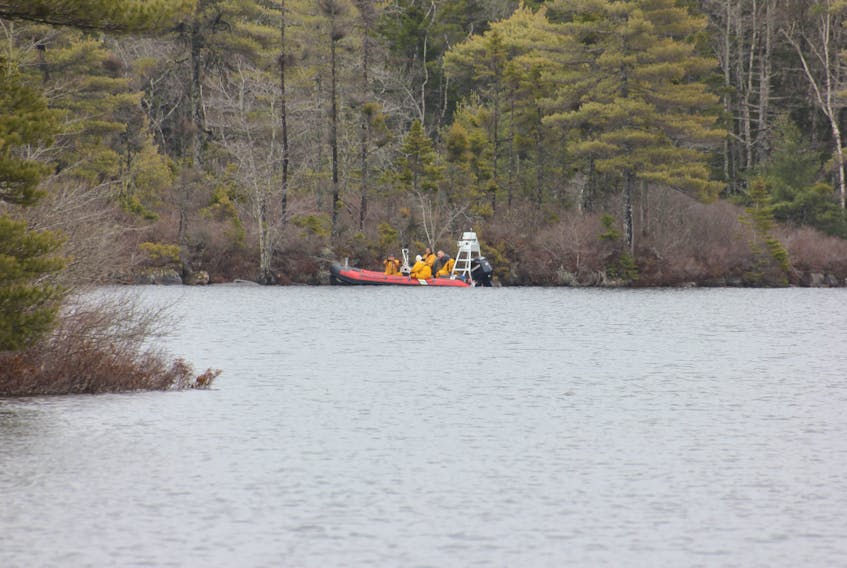 A rescue boat stands by Saturday while RCMP divers search the water of Cloud Lake, where a man went missing Friday while fishing on the lake south of Kingston.