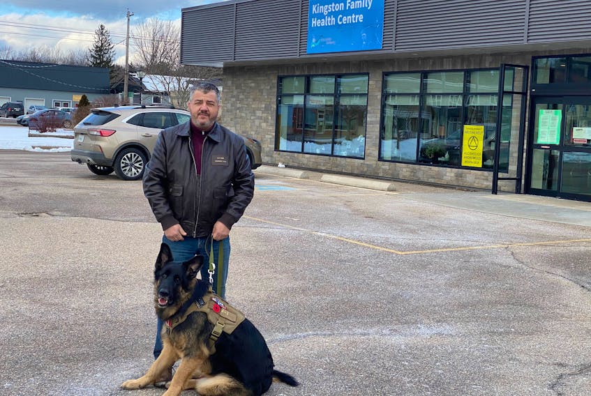 Orphaned patient Michael Hamm stands outside the Kingston Collaborative Family Health Centre with his service dog Storm on Jan. 13, 2020. The clinic opened directly across the street from his house, but it stopped taking new patients before it even opened, so he is still without a doctor after six years on the list.