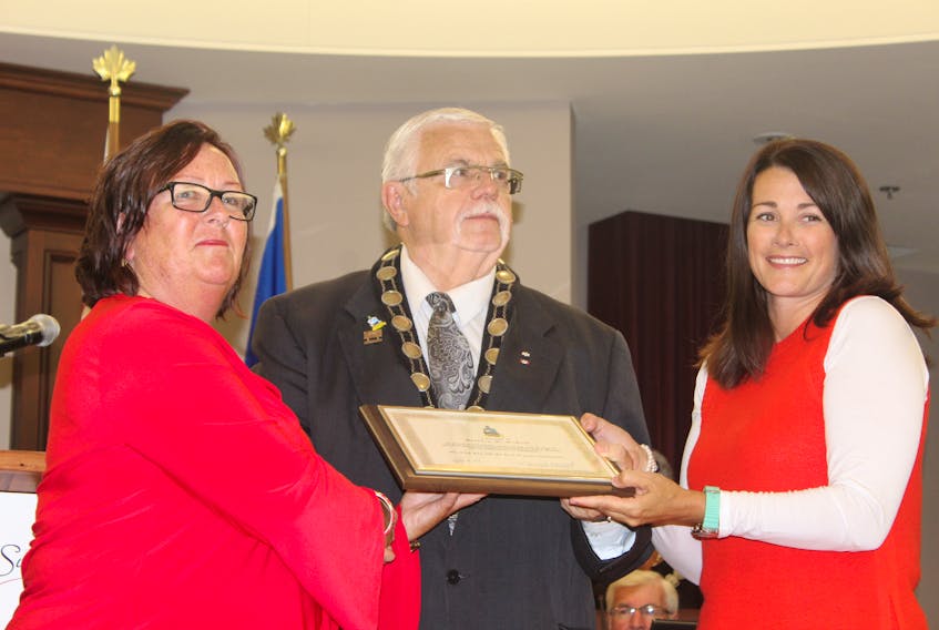 Barbara McNeill accepting an acknowledgment award from Mayor Basil Stewart, and Councillor Carrie Adams (left to right)