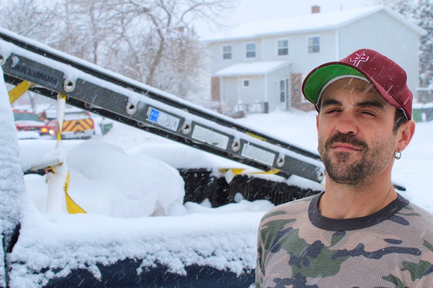 Chris Richard helped save his neighbours from a fire in their half-duplex, located behind him on the right, at Dawson Court in Charlottetown on March 1. He used the ladder, that was strapped to his truck, to help them escape through a second story window.