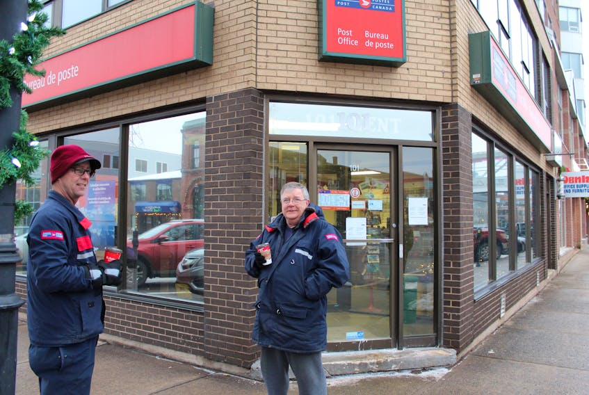 Canada Post employees Norman Dunn, left, and Eric Gauthier stood out front of the Charlottetown office today in protest of the Senate's decision to pass legislation ordering and end to the five weeks of rotating strikes. Employees will be back to work today at 1 p.m.