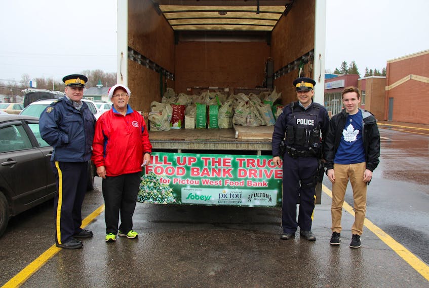 Members of the Pictou County District RCMP join local volunteers in the Fill the Truck Food Drive Friday outside the Sobeys Pictou location. From the left:  Sgt. John Kenny, Pat Roach, Const. Trevor Arsenault and Luke MacDonald stand near the donations already collected for the Pictou West Food Bank.