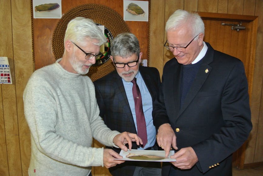 Dr. John Calder, senior geologist with Nova Scotia Lands and Forests, looks over a photo of Isle Haute with Garry Donaldson of the Canadian Wildlife Service and Cumberland-Colchester MP Bill Casey following the announcement Tuesday the towering island in the Bay of Fundy, eight kilometres off the coast of Cape Chignecto will be national wildlife area.