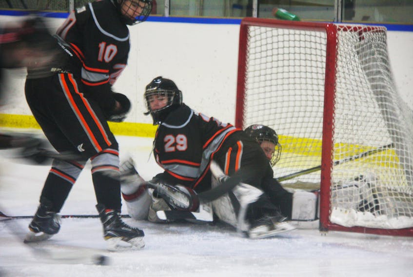 Cape Breton West Major Midget Islanders’ goaltender Kenzie MacPhail keeps his eye on the puck despite a sliding Cole Harbour Wolfpack player taking out his legs, during the Wolfpack’s 4-1 win in East Hants Sunday afternoon. Also pictured from the Islanders is Dell Welton.