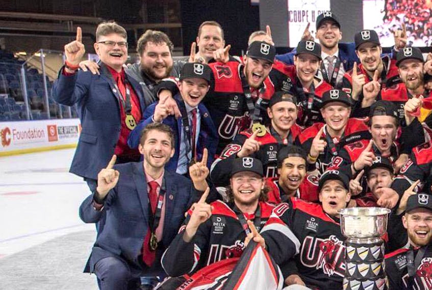 Amherst’s Jordan Hunter (front, left) celebrates with his team, including head coach Gardiner MacDougall (back, left), after the UNB Varsity Reds won a national title March 17 in Lethbridge, Alta.