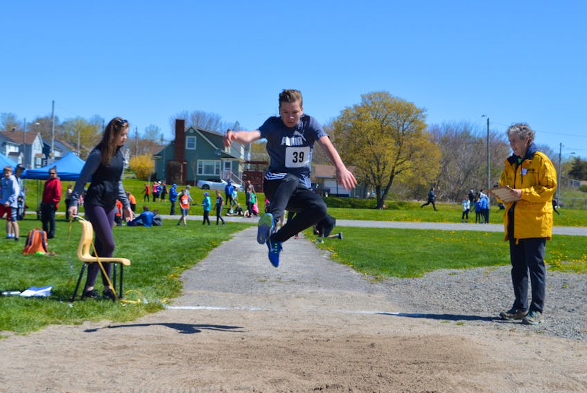 Hunter MacMillan, centre, of Baddeck Academy makes a long jump attempt at the Cape Breton-Victoria Regional School Board district track and field championships on Tuesday at Atlantic Street Field in Sydney. Schools from all across Cape Breton were at the field to compete in a variety of track and field events.
