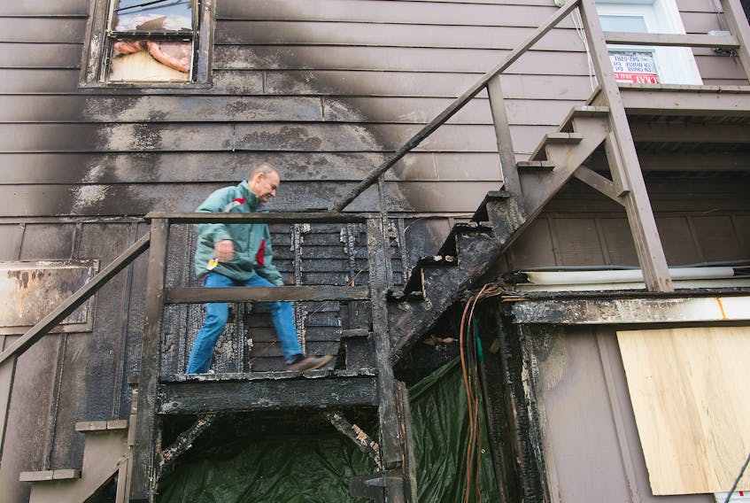 John MacKay of MacKay Real Estate climbs the charred stairs to the apartments above his office to see the damage caused by a fire Thursday night.