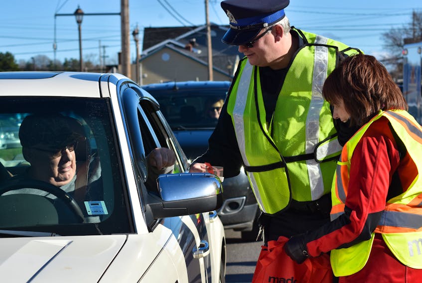 Const. Dave MacDonald of the Kentville Police Service and MADD Canada representative Susan MacAskill present a motorist passing through a check stop on Webster Street in Kentville with information about MADD Annapolis Valley’s Red Ribbon Project.