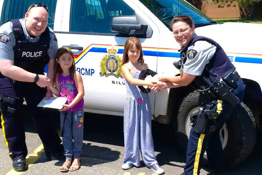 Const. Dave Trenholm and Cpl. Angela Corscadden, of the Windsor Rural RCMP Detachment, present prizes to Maddie MacPhee and Tianna Rhodenizer after drawing the children's names at the conclusion of the Gotcha! campaign.