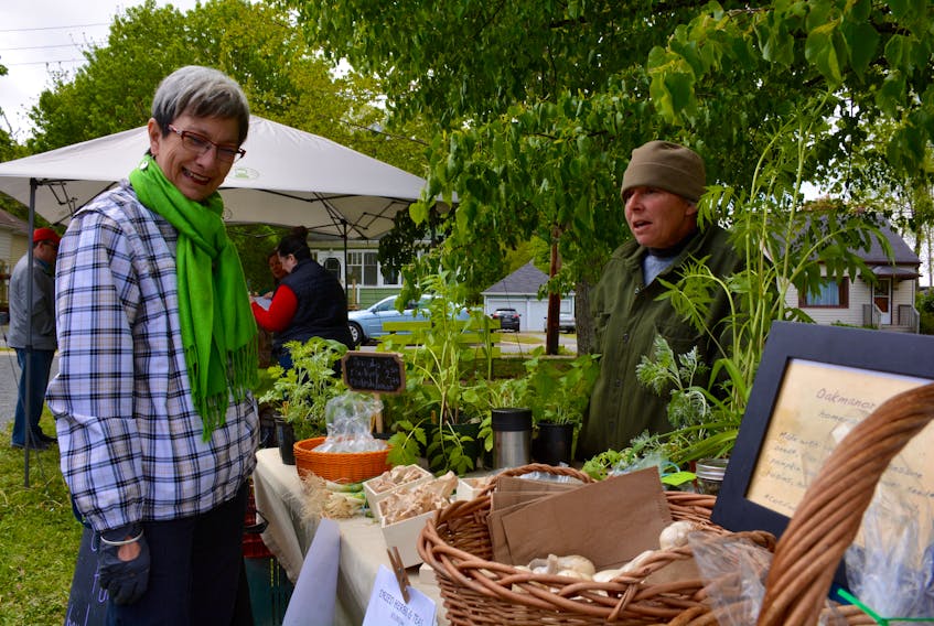 Pam Halverson, left, a resident of Windsor, stopped by the Oak Manor Farms stall (Jamie Cornetta) at the Avon Community Farmers’ Market, picking up some arugula. She said she’s thrilled to have a market like this back in town.