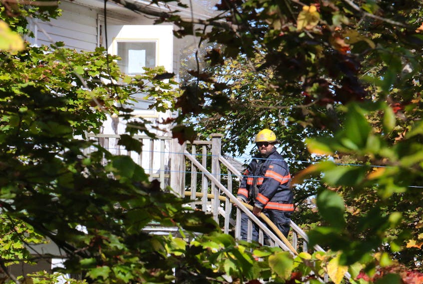 Firefighter Kristopher Lake helps run a hose into the second storey of a 2.5 storey Community Services home on Avon Street Oct. 6. CAROLE MORRIS-UNDERHILL