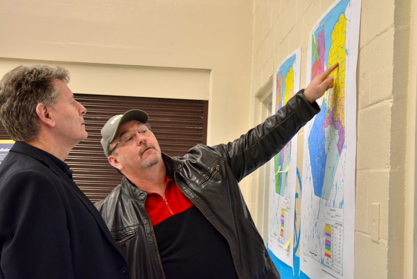 John Heseltine, director of the governance review with Stantec, and Cogmagun resident Adam Brown, discuss one of the electoral district maps that were on display at the Dr. Arthur Hines Elementary School in Summerville.
