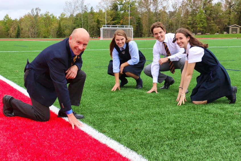 Headmaster Joe Seagram shows off the resilient new turf that's been installed at King's-Edgehill School while Grade 12 students, from left, Téa Racozzi, Nick Cheveie, and Lindsay Hogan, playfully do the same. The students say they're appreciative of the new, top-notch field conditions.