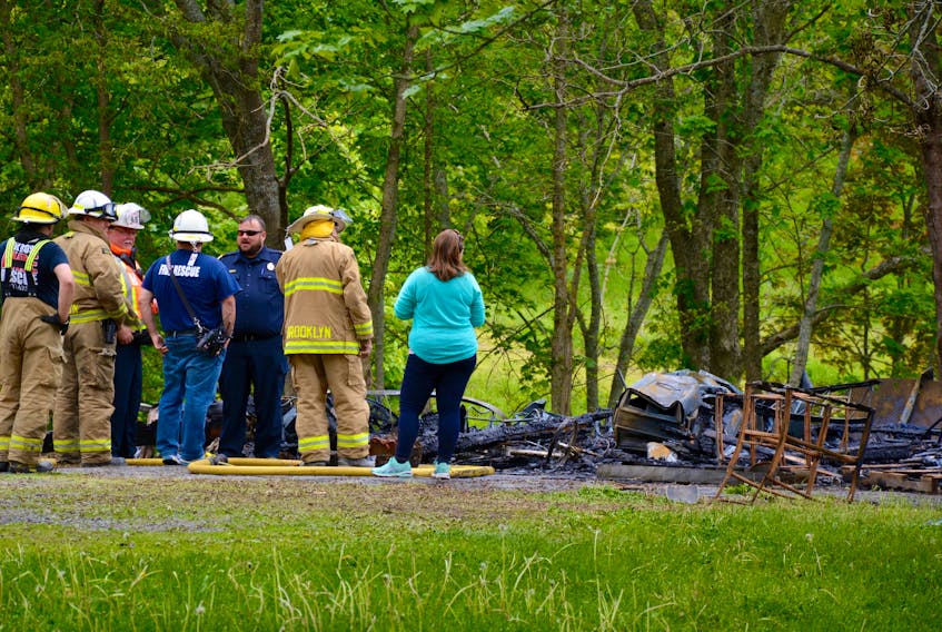 Firefighters and residents inspect the remains of a garage structure, which was levelled by flames on June 11, 2018.