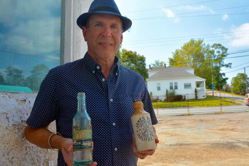 Michael Oxner, owner of the soon-to-be revived James Roué Beverage Company, stands with two of his most prized possessions - one of the original bottles dating back to the company's founding days, and the Bluenose Soda launched by the founder's son, W.J. Roué.