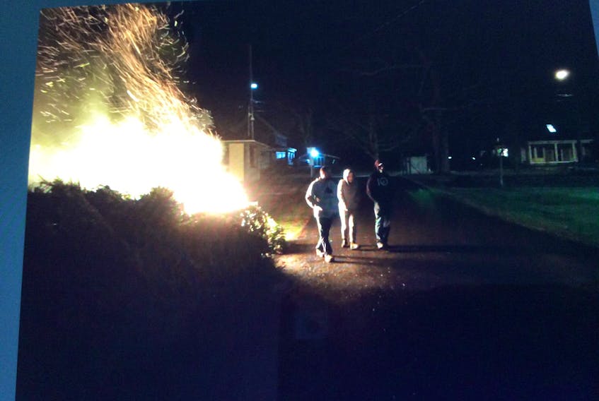This picture, via Paul Morton’s Facebook page, shows discarded Christmas trees burning on HMCC grounds the evening of Jan. 13, 2018. The three individuals pictured next to the flames are not suspected, Morton said.
