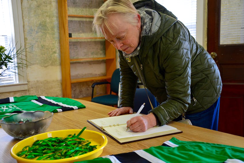Margie Seeley signs a book of condolences, organized by the Windsor Hockey Heritage Society, that will be sent to the community of Humboldt, Saskatchewan, following a horrific tragedy that claimed the lives of 16 people traveling with the Humboldt Broncos junior hockey team.