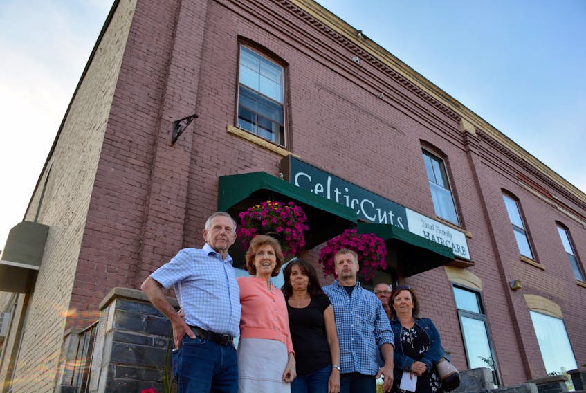 CelticCuts owners, staff and their partners stand in front of Dufferin Place, where the hair salon is located. They're concerned about what a new development plan for the area could mean for them.