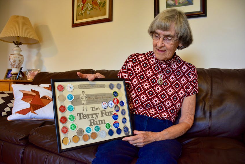 Mary Ruth Cochrane is pictured with a Terry Fox Run plaque that is covered in stickers from all of the runs she’s participated in since the beginning.