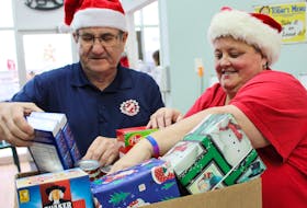 Eric Ferrish, left, and Sue Gallant, pack a box of non-perishables and presents for the annual Kin Appeal, by the Summerside Kinsmen and Kinettes, who fill about 600 hampers for about 200 local families each Christmas season. MILLICENT MCKAY/THE GUARDIAN