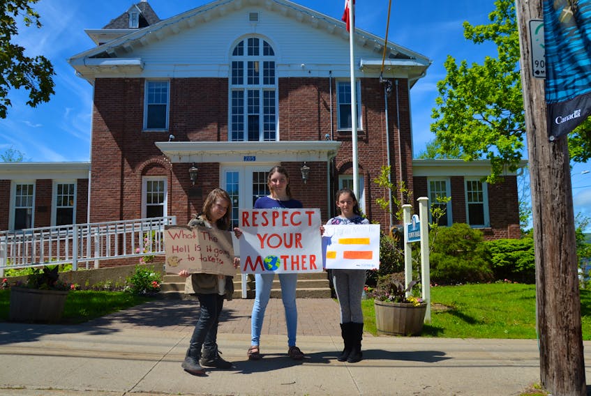 Jonah Rubin Flett, Sophie Bouchard Todd, and Sunna Bouchard Todd hold signs in front of town Hall in Annapolis Royal. They were there Friday, June 14 as part of the global Fridays For Future movement for climate justice started by Swedish teen Greta Thunberg. –