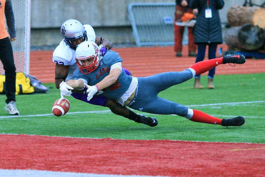 Acadia’s Cordell Hastings tries to focus on the ball while his opponent from the Gaiters readies for a tackle.