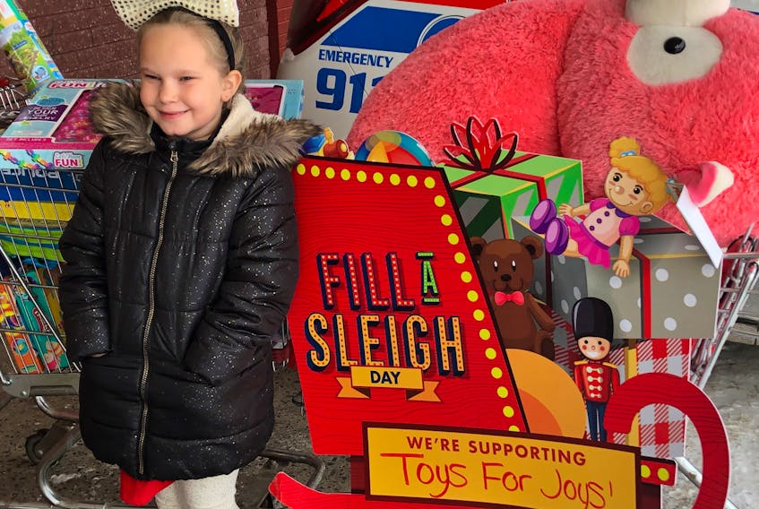 Autumn Decker donates toys to the Fill a Sleigh Day held recently as part of Toys for Joys. The annual fundraising effort, which also includes a popular dance, raised $26,000 this year to give Christmas toys to children in need.