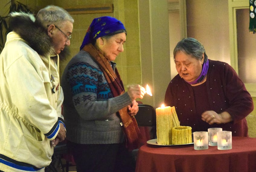 Elizabeth Penashue lights a candle to symbolize healing. Penashue, Ken Mesher (left) and Berta Holieter each lit one on behalf of the survivors of residential schools.