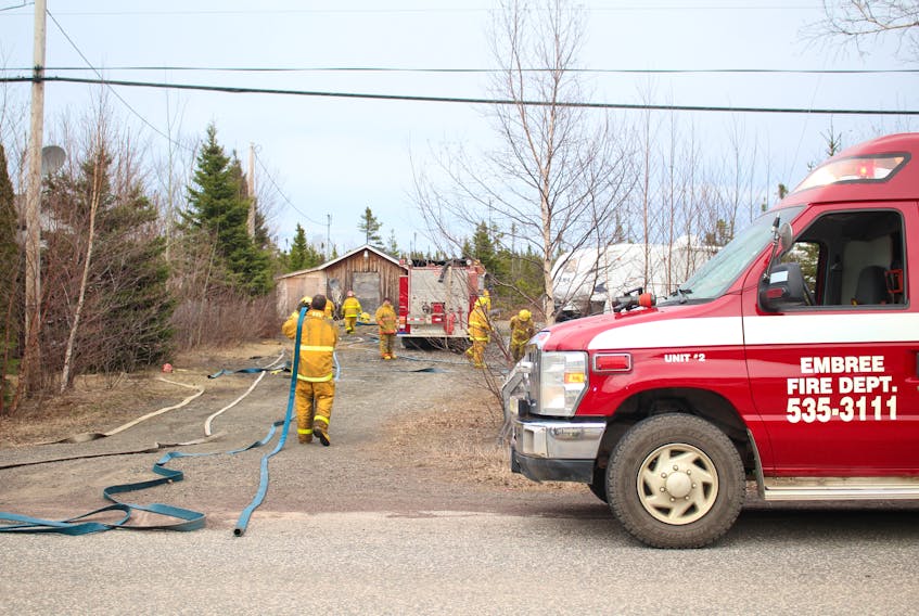 Members of the Embree Fire Department load their gear and roll hoses after they extinguished a brush fire April 26.