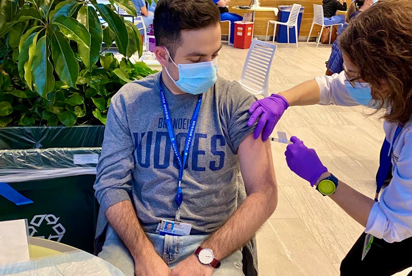 Clinical epidemiologist Lewis Novack gets a shot of the Moderna COVID-19 vaccine at the Brigham and Women’s Hospital in Boston. Novack is paart of a team reviewing a single-dose candidate manufactured by Johnson and Johnson.