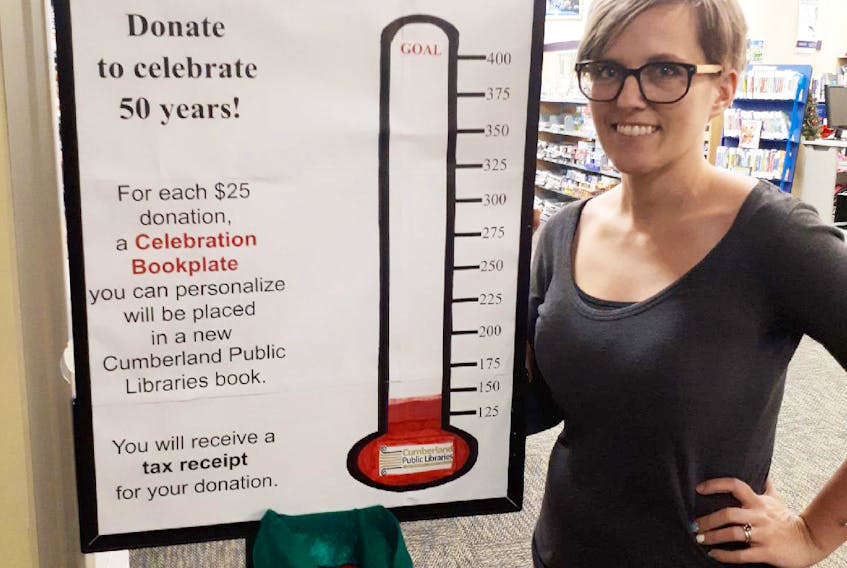 Cumberland Public Libraries secretary Kristy Brown looks over a fundraising sign at the Four Fathers Memorial Library in Amherst. Libraries across the county, like those around the province, are continuing to face a financial crunch in light of a funding freeze.