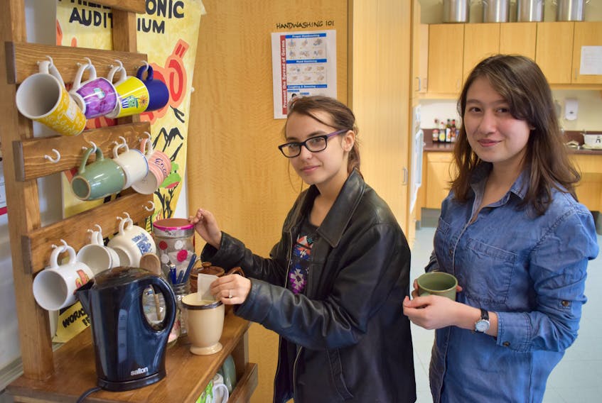 Northumberland Regional High School students Dayveen Earp, left, and Sarah Campbell make tea while on break from classes at the school. The students have set up a Mugs 2 Go rack where students can use reusable mugs.