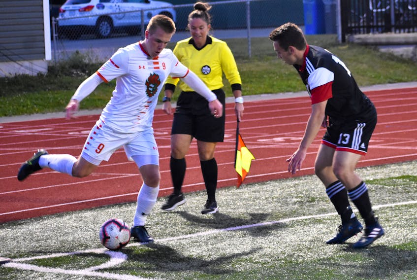 Charlie Waters of the Cape Breton Capers, right, attempts to work his way around Nick Ellingwood of the New Brunswick Reds during Atlantic University Sport men’s soccer action at the Cape Breton Health Recreation Complex on Friday. Cape Breton won the game 2-1.
