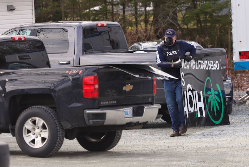 Police cart away a sign from a cannabis dispensary on Caldwell Road in Cole Harbour on Wednesday, Dec. 23, 2020. Several dispensaries along the road were raid by officers with the Halifax District RCMP street crime enforcement unit.